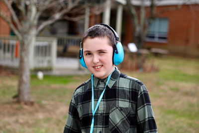 Student with anti-noise earmuffs smiling in school garden