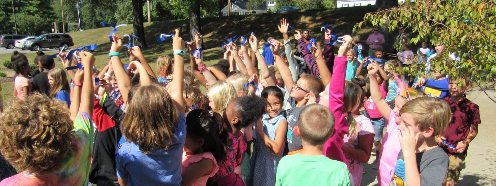 Group of students holding blue ribbons in the air