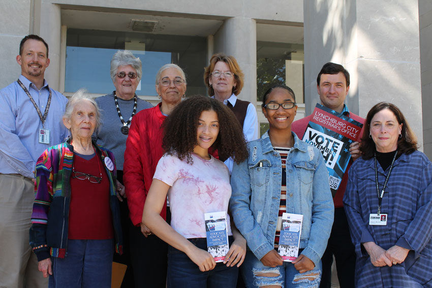 People outside school holding voter registration promotional materials