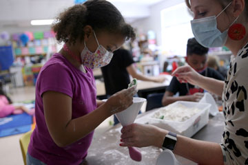 Masked child in classroom with teacher