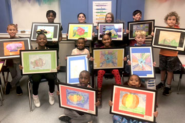 12 students holding framed artwork