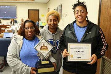 Three custodians in School Board Room holding awards