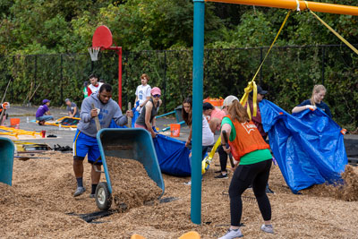 E. C. Glass football player emptying wheelbarrow during playground build project