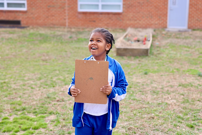 Student outside holding clipboard