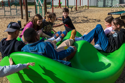 Students on playground equipment while one wears camera