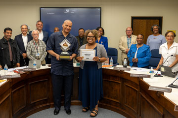 Custodian and principal holding award at School Board meeting