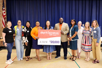 J.Crew representative with LCS administrators and staff holding donation sign 