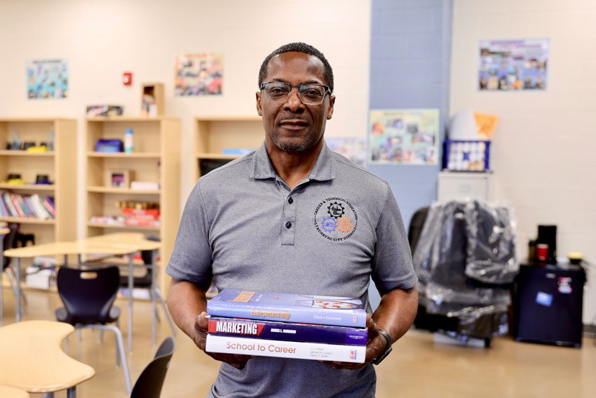 Teacher Andrew Kelso holding marketing books