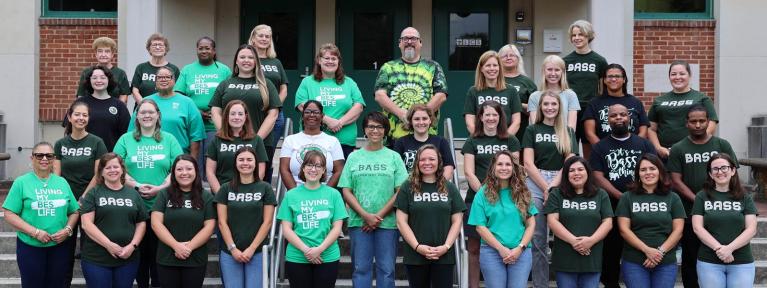 Bass staff standing on front steps of the school