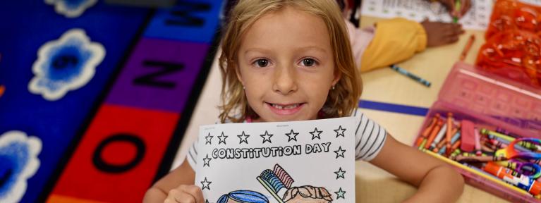 Smiling student holding Constitution Day worksheet