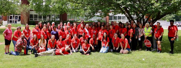 School staff in matching shirts standing in from of building