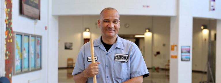 Custodian holding broom in school lobby